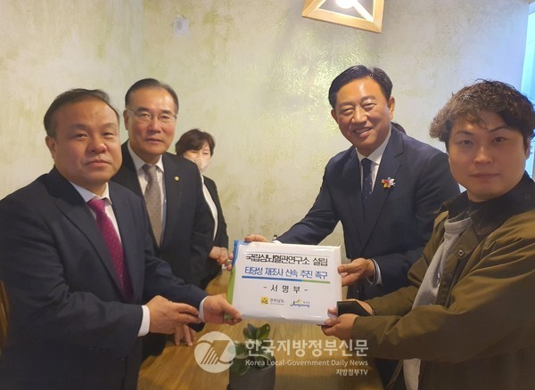 지난 11월 김한종 장성군수(뒤의 오른쪽)는 지역구 이개호 국회의원(뒤의 왼쪽), 전남도‧장성군 관계자와 함께 KD, 기획재정부 관계자를 만나 연구소 설립을 청원하는 장성군민 서명부를 전달하고 있다(사진=장성군청)