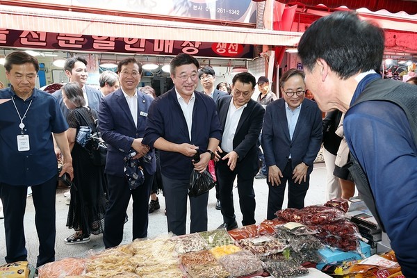 윤호중 행정안전부 장관(가운데)이 24일 오후 서울 금천구 비단길 현대시장을 방문하여 민생회복 소비쿠폰 사용가능 매장 스티커를 부착하며 상인들을 격려하고 있다.(사진=김미숙 기자/행정안전부)